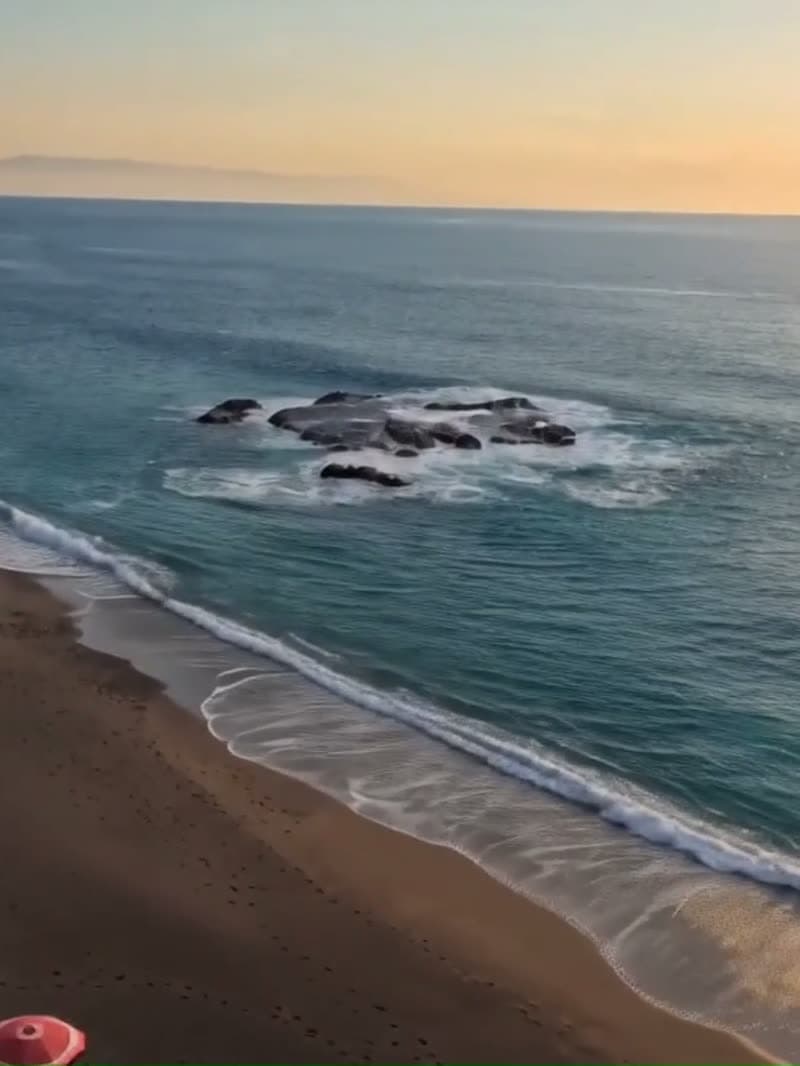 Lo scoglio al largo di Spisone visto dall'alto, con la battigia scura e la schiuma delle onde